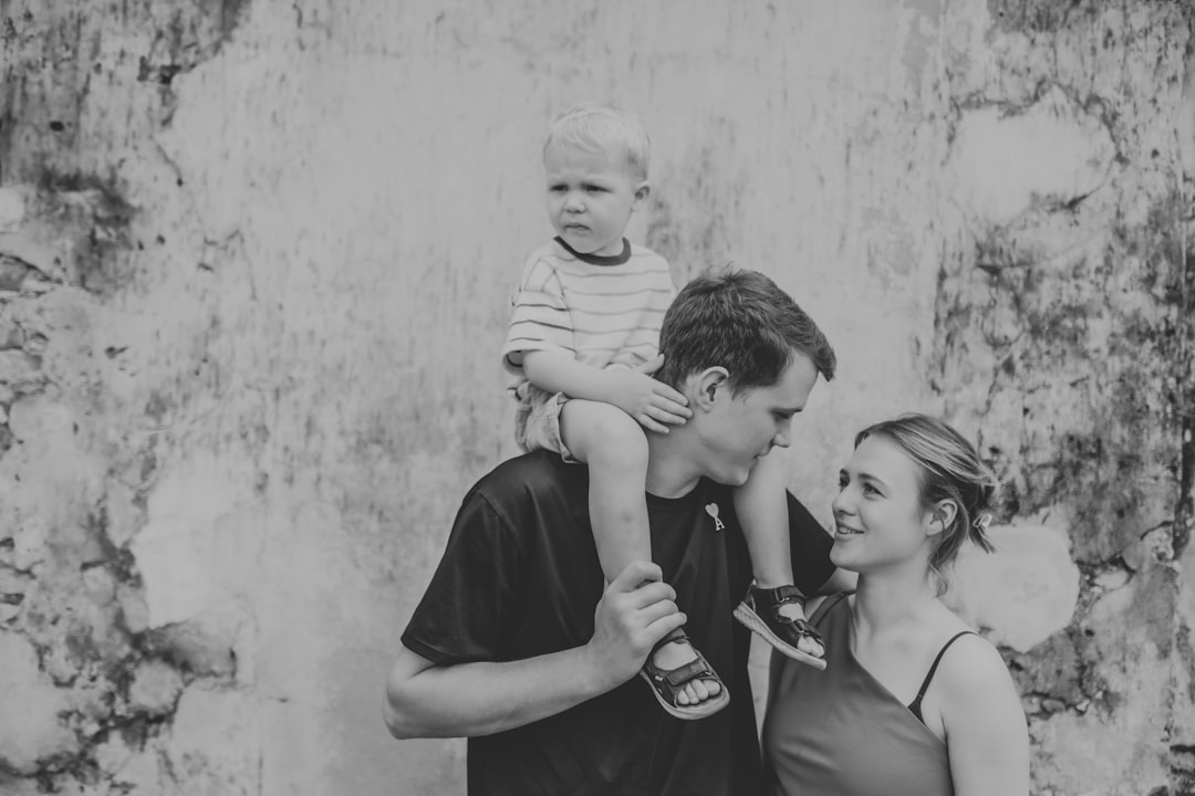 Father carrying son on shoulders, mother beside them.